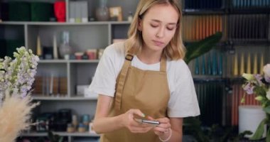 Çiçekçi kadın ressam çiçek dükkanı reklamı için güzel bir buket alet tabletinin videosunu çekiyor ya da kaydediyor. Yavaş çekim.