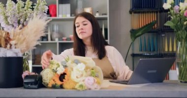 Young business woman professional designer, florist decorator using laptop at the floral store they checking the inventory of shop. Small family business concept. Slow motion.