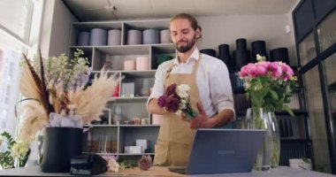 Man owner of the flowers shop entrepreneur make a beautiful composition. Caucasian male florist working in modern flower store. Slow motion.