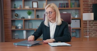 Workflow in office where attractive fatigued hardworking adult female office manager closing her laptop,taking off her glasses ,closing eyes becouse feeling the pain in her temples after overtime work