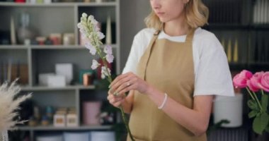 Close up of woman florist hands taking blossoms and cutting stems of flower. Florists work. Close-up portrait. Slow motion.