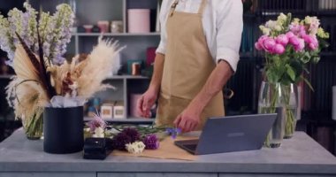 Professional florist working a flower shop. Bearded man in an apron makes a bouquet of fresh flowers. Small own business. Slow motion.
