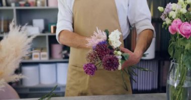 Close up hands of professional florist making bouquet of blossoms at table. Man making preparing bouquets at own flower shop. Slow motion.