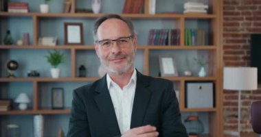Business portrait of good-looking successful experienced adult bearded ceo in business clothes standing in front of camera with crossed arms and sincerely smile on his workplace background