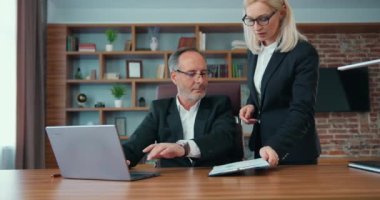 Good-looking experienced professional bearded businessman signating business documents brought by his pretty hardworking light haired woman-helper,workflow in office,accelerated motion