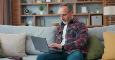 Yakışıklı, yetenekli, sakallı, gözlüklü, rahat koltukta dinlenen ve bilgisayarında bilgi sörfü yapan bir adam.