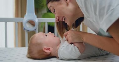 Mutlu anne küçük bebek güneşiyle oynarken gülümser. Ebeveyn, çocuk kızı eğlendirir. Anne ve küçük bebek, yakın plan.