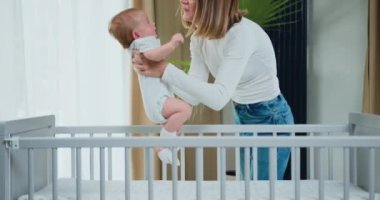 Neşeli anne, küçük oğlunun başının üstünde yükselir. Genç anne yeni doğmuş çocuğunu kucağında tutuyor. Mutlu annelik ve çocukluk. Yavaş çekim.