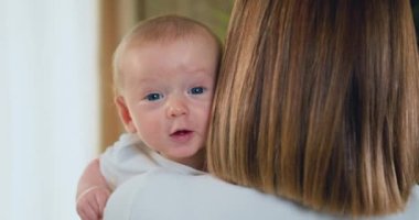 Gülümseyen beyaz küçük bebeğin portresi. Anne kucağında yeni doğmuş bir bebek tutuyor. Annelik kavramı. Yavaş çekim.