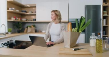 Modern mutfağa bakan çekici, gülümseyen sarışın kadın portresi. Bin yıllık beyaz bir kız ön portreyi yakın çeksin. Yavaş çekim