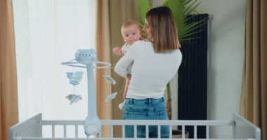 Cozy Warm Kids 'in yatak odasında kucağında yeni doğmuş tatlı bir erkek bebek tutan mutlu bir anne. Evdeki annesinin kolunda yeni yürümeye başlayan bebeğe yakın dur. Çocukluk kavramı, yeni hayat, ebeveynlik