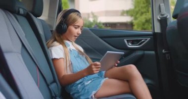 Hoş, güler yüzlü, 12 yaşında, kablosuz kulaklıklı sarışın bir kız. Arabalarda oturuyor, çantalarında oyunlar oynuyor, zaferle seviniyor.