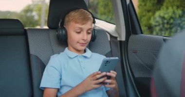 Çekici, pozitif sarışın, 10 yaşında, kablosuz kulaklıklı bir çocuk. Cep telefonunu arkadaşlarıyla sohbet etmek için kullanıyor ya da internette en sevdiği şarkıları arıyor. Arka koltukta oturuyor.