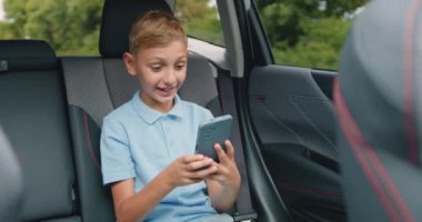 Aracın arka koltuğunda giderken akıllı telefonuyla görüntülü sohbetten hoşlanan, kaygısız, modern 10 yaşında bir çocuk.