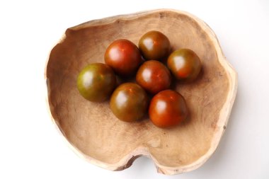 Tahta bir masadaki ahşap bir kasede bir sürü kahverengi domates, yerel çiftçilerden yeni toplanmış taze organik sebzeler. Yiyecek konsepti.