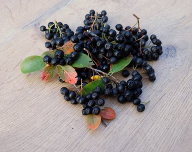 Böğürtlen, Aronya çileği, bahçedeki ahşap bir masanın üzerinde yapraklar..