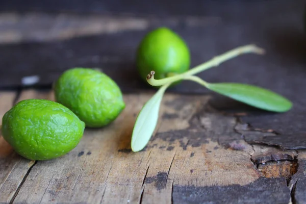 Foglie di ulivo verde e olive su sfondo squallido tavolo in legno. Posa piatta, vista dall'alto. Design mediterraneo. — Foto Stock