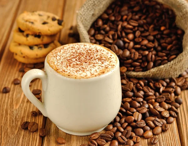 Café com espuma e grãos de café em um saco — Fotografia de Stock