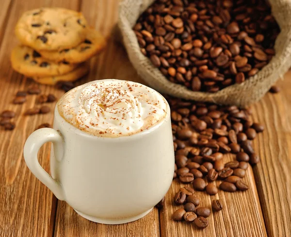 Café com espuma e grãos de café em um saco — Fotografia de Stock