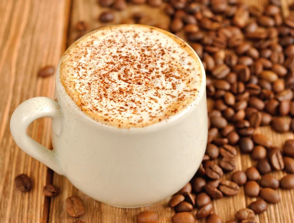 Kaffee mit Schaum und Kaffeebohnen — Stockfoto