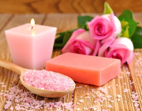 Sal marina, rosa, jabón y una vela encendida —  Fotos de Stock