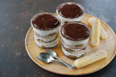 Kahverengi arka planda bir bardak tiramisu tatlısı.