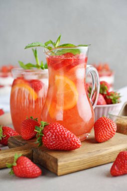 Gri arka planda çilekli ve limonlu yaz limonatasını tazeliyorum.