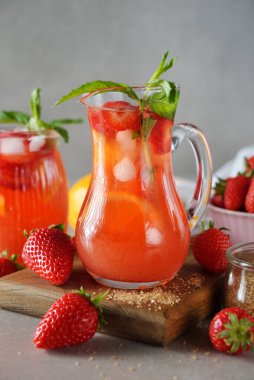 Gri arka planda çilekli ve limonlu yaz limonatasını tazeliyorum.