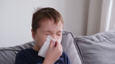 Küçük bir çocuk hasta, burnunu siliyor. Grip, grip, enfeksiyon, virüs