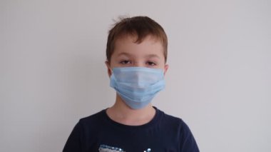Küçük çocuk tıbbi koruyucu maskesini çıkardı.
