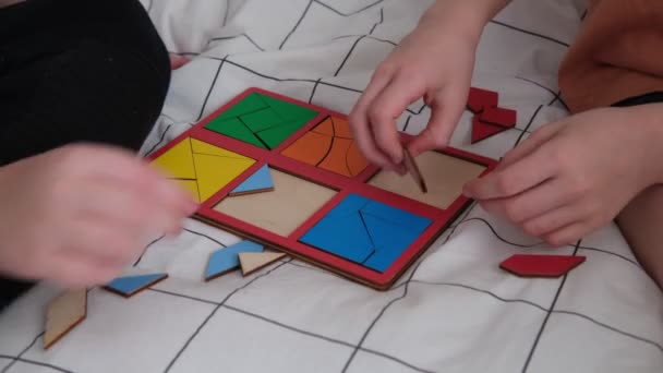 Μικρά παιδιά συλλέγουν ξύλινο εκπαιδευτικό παιχνίδι, τα χέρια κοντά — Αρχείο Βίντεο