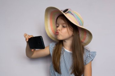 Küçük tatlı kız akıllı telefondan selfie çekiyor.