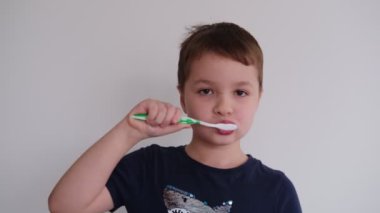 Küçük çocuk diş fırçası ve diş macunuyla dişlerini fırçalıyor.
