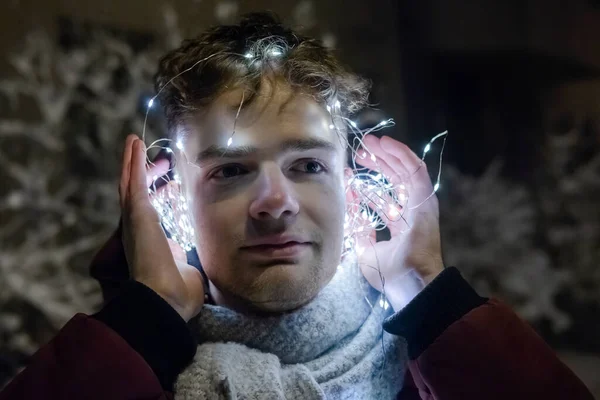 Kulaklıklı genç yakışıklı adam çelenk, yeni yıl ve noel konsepti.
