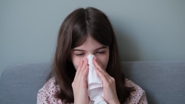 Niña, una adolescente está enferma de gripe, se sopla la nariz en una servilleta — Vídeos de Stock