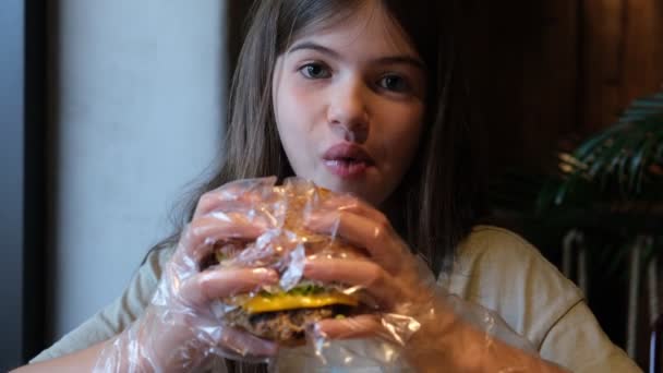 Mignonne petite fille, adolescent manger hamburger dans le café — Video