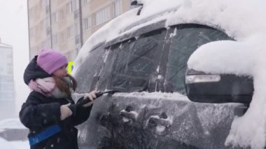 Yavrum, tatlı bir kız karlı bir kış gününde arabayı kardan temizler.