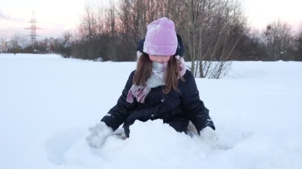 Маленька мила дівчинка грає зі снігом, розважається. Дитячі зимові ігри концепція відпустки — стокове відео