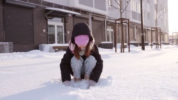 Μικρό χαριτωμένο κορίτσι που παίζει με το χιόνι, διασκεδάζει. Παιδικά παιχνίδια χειμώνα έννοια διακοπές — Αρχείο Βίντεο