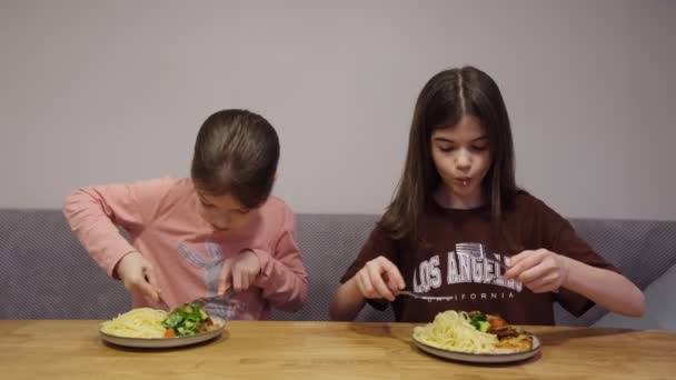 Dzieci, siostry jedzą obiad przy stole. — Wideo stockowe