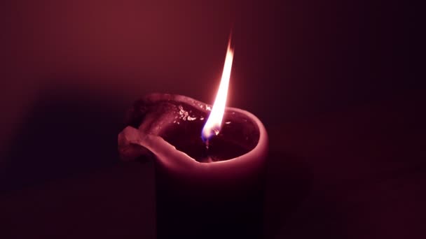 Brennende lila Kerzenflamme auf dunklem Hintergrund — Stockvideo