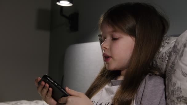 Küçük kız gece akıllı telefonuyla oturuyor, oyunlar, online öğrenim — Stok video