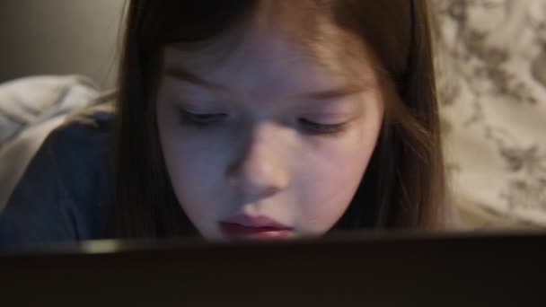 Küçük bir kız geceleri dizüstü bilgisayar kullanıyor, oyunlar oynuyor, videolar izliyor, sosyal ağlardan arkadaşlarıyla iletişim kuruyor, çocukların cihazlara olan bağımlılığı, konsept — Stok video