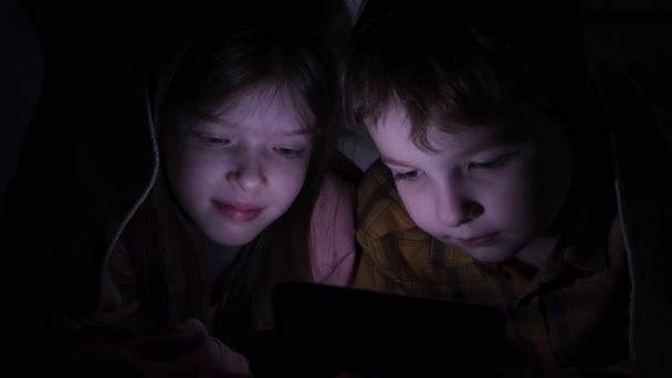 Geceleri yorganın altında telefonu olan küçük çocuklar. — Stok video