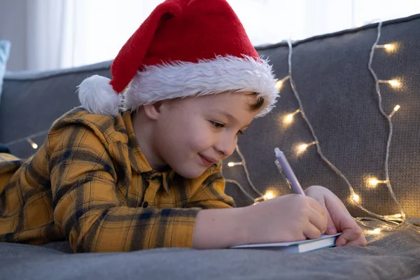 Küçük çocuk Noel Baba 'ya yeni yıl ve Noel için mektup yazıyor.
