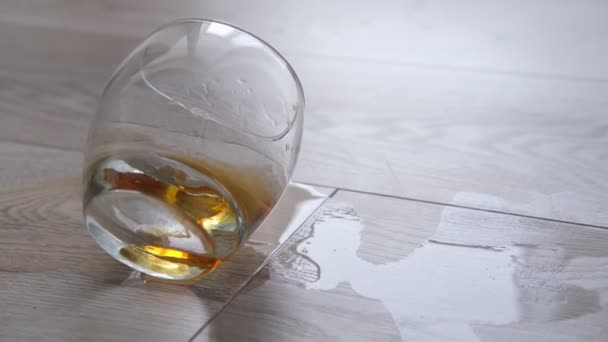 A glass of whiskey or cognac is on the floor. Alcoholism, loneliness concept — Wideo stockowe