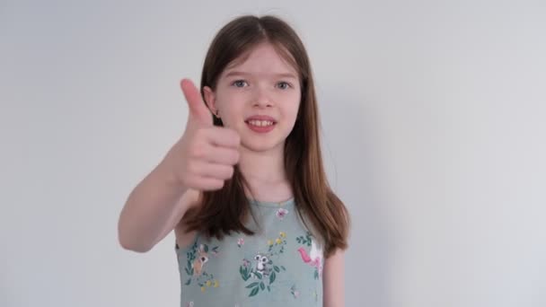 可愛い女の子が親指を立ててカメラを見ている。カメラに微笑む、 OKサイン. — ストック動画