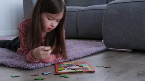 Malá holčička leží na podlaze a sbírá dřevěné tetris puzzle — Stock video
