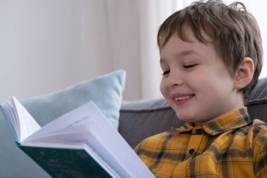 Küçük şirin çocuk kitap okuyor ve gülüyor.