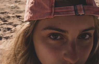 Genç kadın portresini sahilde yaz şapkasıyla kapatın..